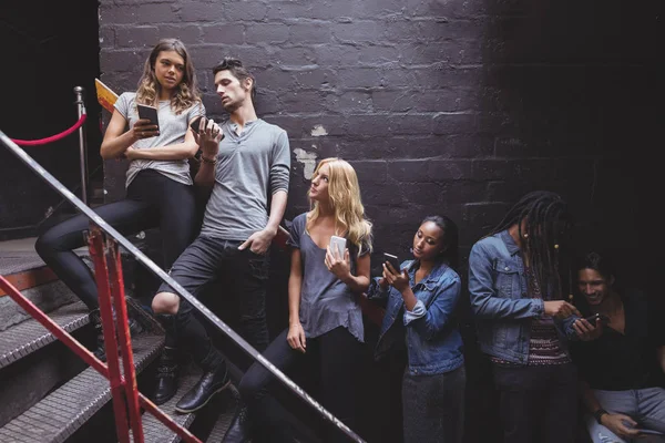 Друзі використовують телефон в нічних клубних сходах — стокове фото