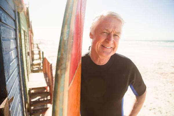 Homme âgé souriant debout près de la planche de surf — Photo