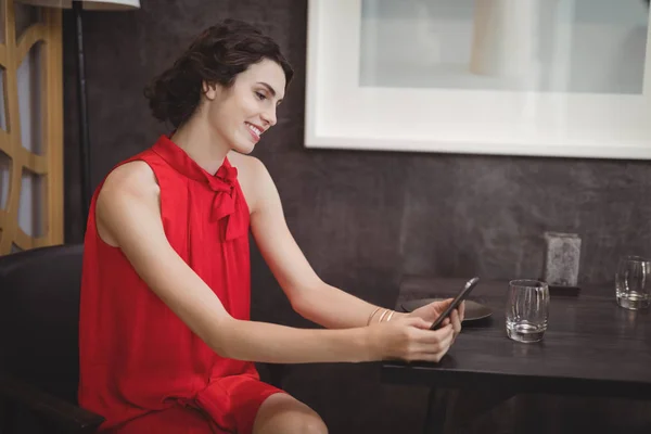 Красивая женщина с телефоном за столом — стоковое фото