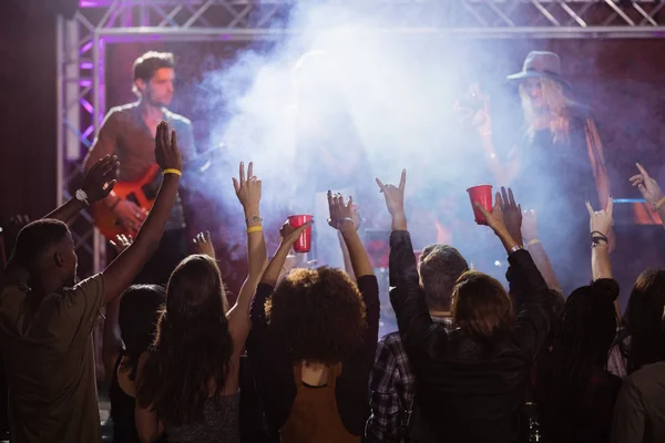 Aficionados con los brazos levantados disfrutando concierto de música — Foto de Stock