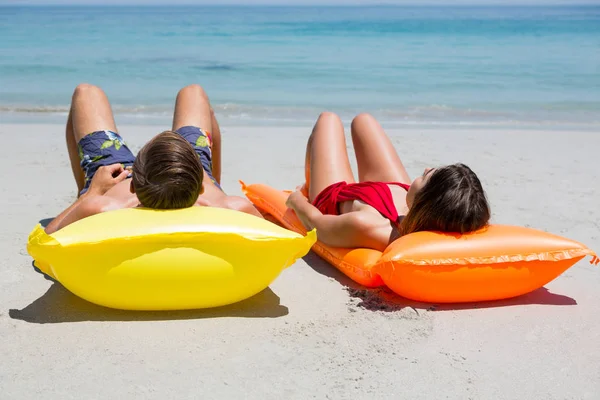 Par liggande på pool flotte på stranden — Stockfoto