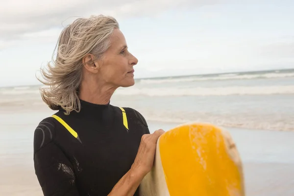 Donna che distoglie lo sguardo mentre porta la tavola da surf — Foto Stock