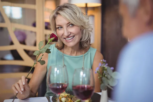 Mature woman smelling a rose flower — Stock Photo, Image