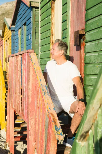 Uomo anziano che distoglie lo sguardo mentre siede sui gradini — Foto Stock