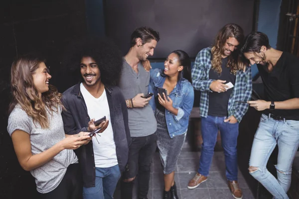 Amigos alegres usando el teléfono juntos — Foto de Stock