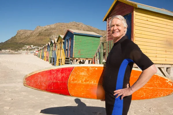 Uomo anziano sorridente che trasporta tavola da surf — Foto Stock