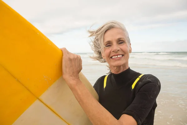 Sonriente mujer mayor sosteniendo tabla de surf —  Fotos de Stock