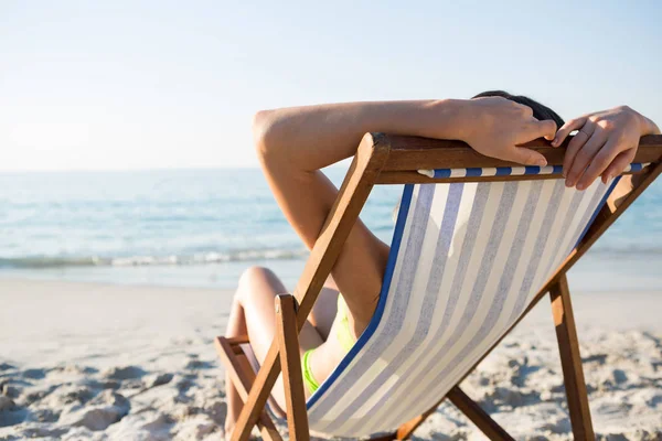 Vrouw rustend op lounge stoel op strand — Stockfoto