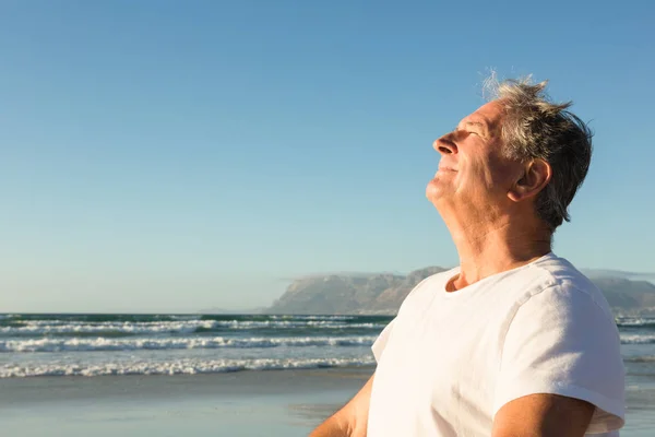 Uomo anziano sorridente che si rilassa in spiaggia — Foto Stock