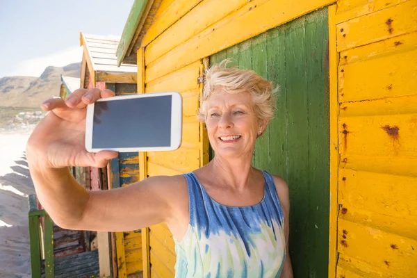 Mulher tomando selfie enquanto estiver contra a cabana — Fotografia de Stock