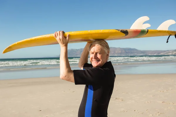 Senior homme portant planche de surf à la plage — Photo