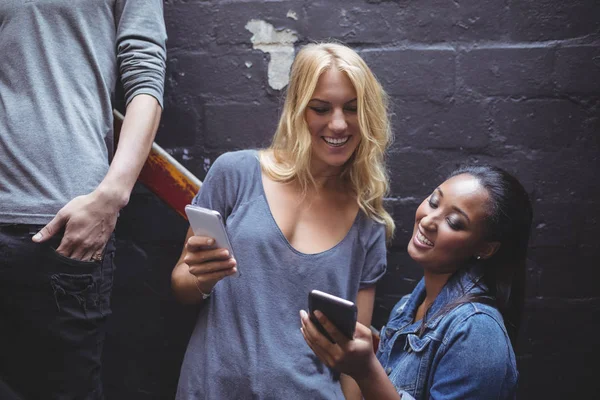 Mujer con amigo usando el teléfono móvil — Foto de Stock