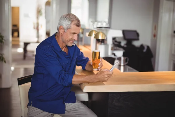 Zralý muž pomocí telefonu a pivo — Stock fotografie