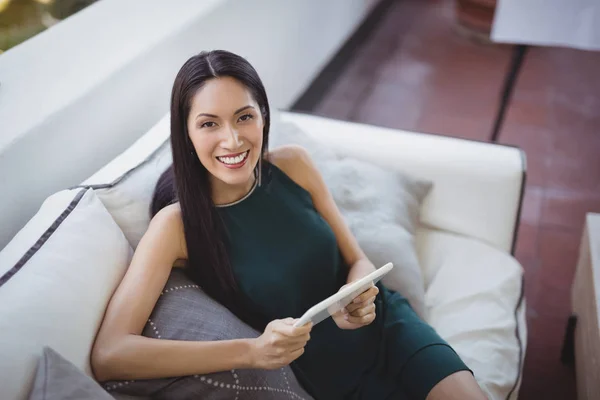 Жінка тримає планшет, розслабляючись на дивані — стокове фото