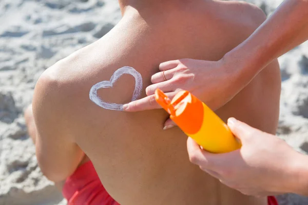 Женщина, создающая форму сердца с солнцезащитным кремом — стоковое фото