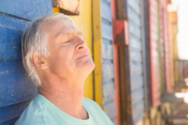 Starszy człowiek relaksujący przez beach hut — Zdjęcie stockowe