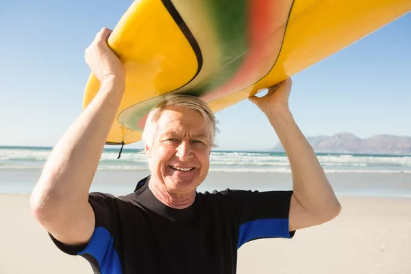 Senior man carrying surfboard at beach — Stock Photo, Image