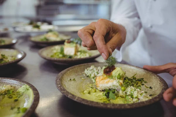 Чоловічий шеф-кухар прикрашає закуску в тарілці — стокове фото