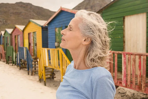 Frau mit geschlossenen Augen steht gegen Hütten — Stockfoto