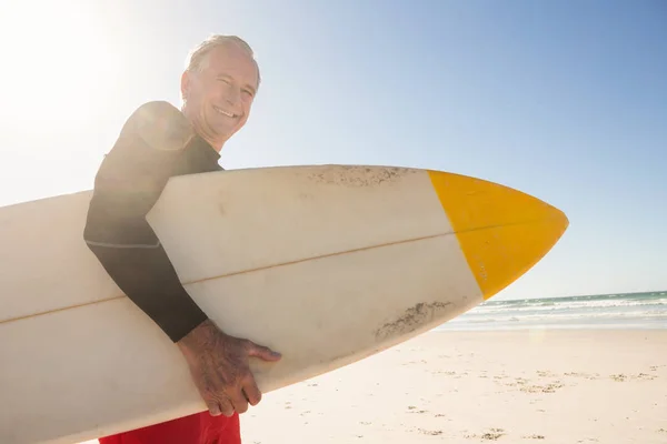 Uomo anziano sorridente che tiene tavola da surf — Foto Stock