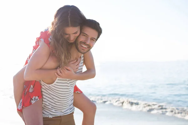 Hombre piggybacking su novia en la playa — Foto de Stock