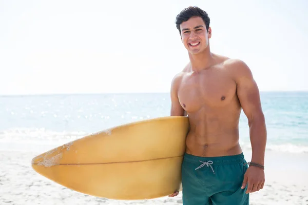 Gespierde man met surfplank op strand — Stockfoto