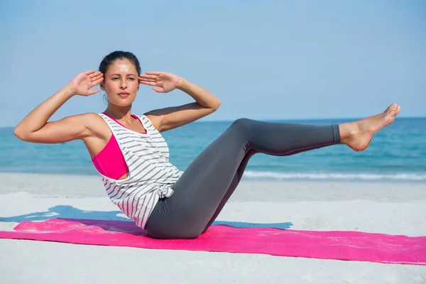 Donna che esercita sul tappeto in spiaggia — Foto Stock