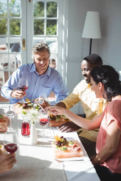 Friends using tablet while having meal — Stock Photo, Image