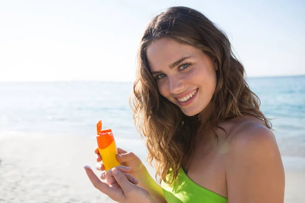 Woman holding sunscreen at beach — Stock Photo, Image