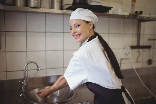 Женщина-повар моет руки на кухне — стоковое фото