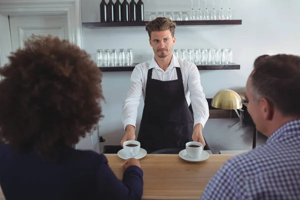 Waiter serving coffee to costumer at counter — Stock Photo, Image