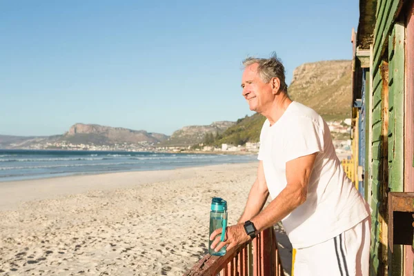 Starszy człowiek stojący na poręczy na plaży — Zdjęcie stockowe