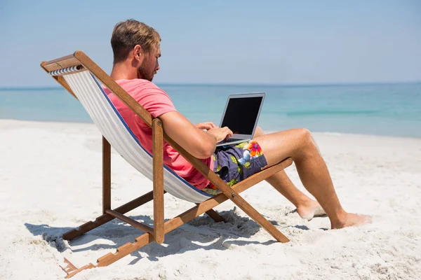 Mann benutzt Laptop am Strand — Stockfoto