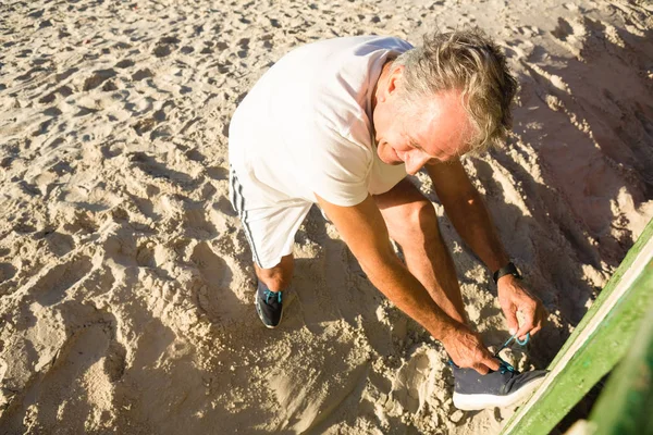 Uomo allacciatura lacci delle scarpe mentre in piedi sulla sabbia — Foto Stock