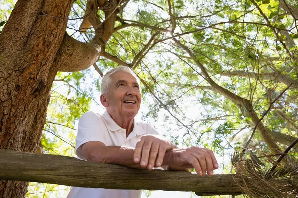 Hombre mayor apoyado en valla de madera — Foto de Stock
