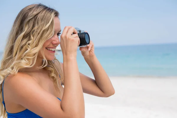 Mujer fotografiando de pie en la playa —  Fotos de Stock