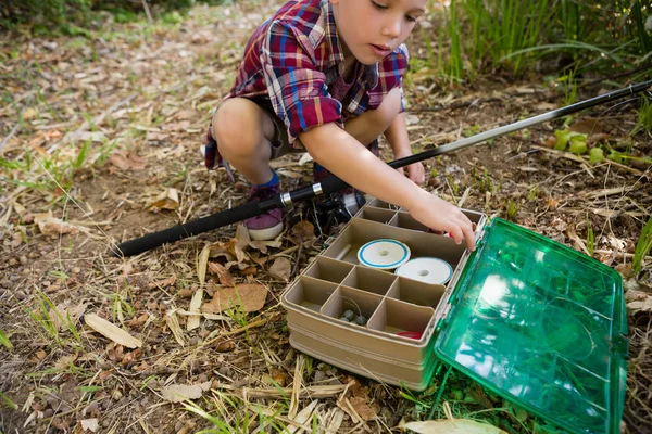 Boy with fishing rod searching in box — Stock Photo, Image