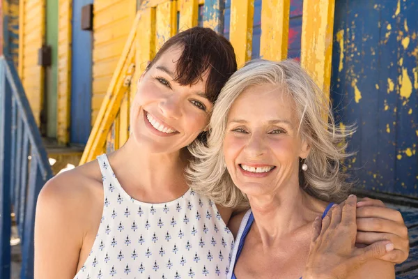Mother and daughter standing against wall — Stock Photo, Image