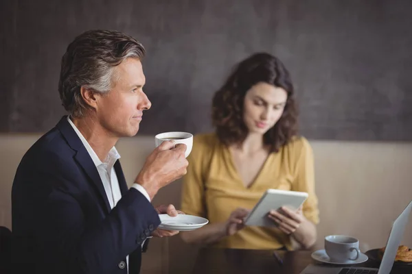 Бизнесмен пьет кофе в то время как коллега — стоковое фото