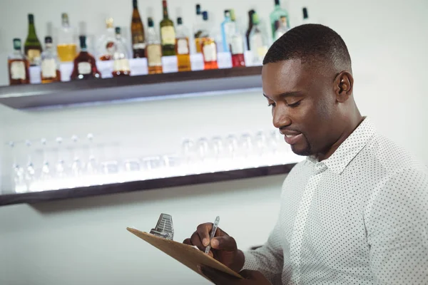 Escritura de licitación en el portapapeles en el mostrador del bar — Foto de Stock