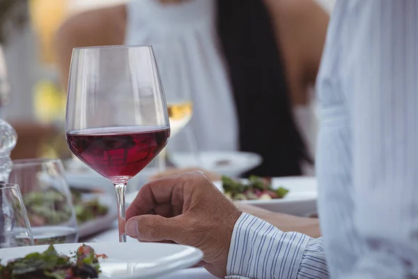 Homem segurando copo de vinho enquanto tendo refeição — Fotografia de Stock