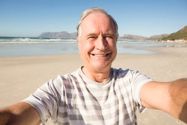 Usměvavá starší muž, který stojí na pláži — Stock fotografie