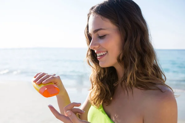 Frau schüttet am Strand Sonnencreme auf Finger — Stockfoto