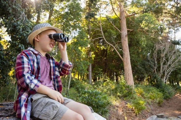 Boy looking through binoculars in forest — Stock Photo, Image