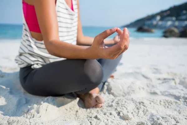 Женщина медитирует, сидя на песке на пляже — стоковое фото