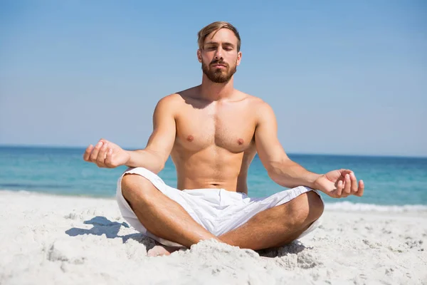 Homme torse nu méditant à la plage — Photo