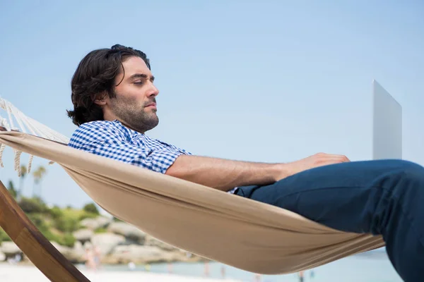 Hombre usando el ordenador portátil mientras que se relaja en hamaca — Foto de Stock