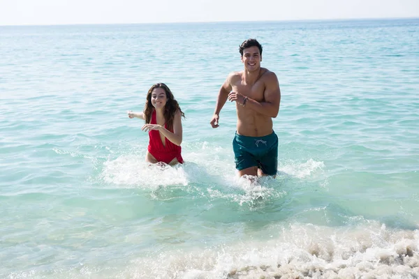 Пара, бегущая в море на пляже — стоковое фото