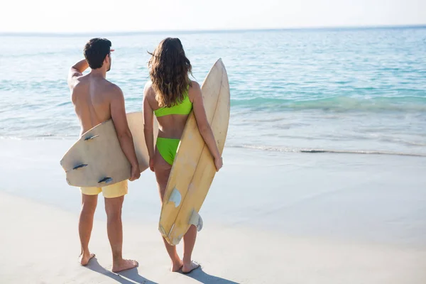 Deski surfingowe gospodarstwa para na plaży — Zdjęcie stockowe