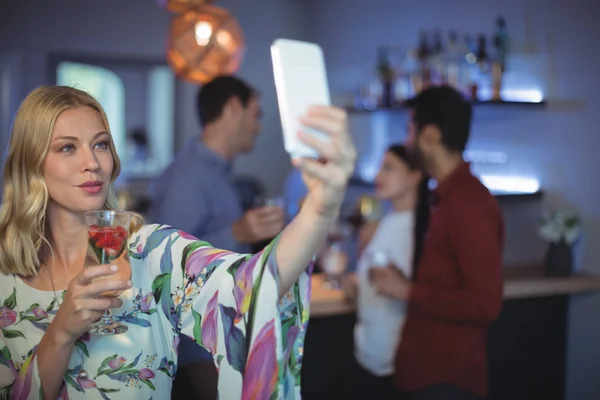 Женщина держит стакан напитка во время селфи — стоковое фото